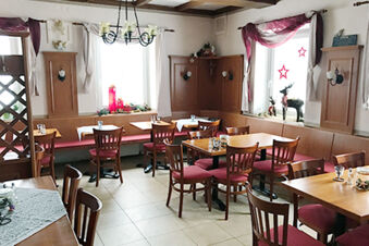 Dining area at Landgasthof Hotel Hammerm&uuml;hle with wooden tables, chairs, red cushions, and Christmas decorations on windowsills