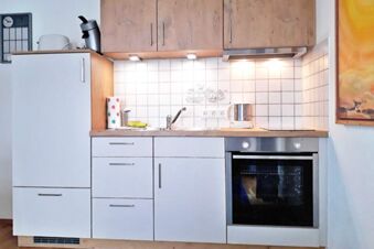 Modern kitchen area at Pension G&auml;stehaus Alpenblick with white cabinets, oven, sink, and paper towel holder visible