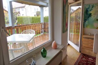 Interior view of Pension G&auml;stehaus Alpenblick showing a room with open glass door to a wooden balcony with table and chairs