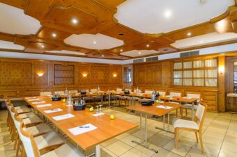 Meeting room with wooden panel walls and ceiling, arranged tables and chairs, notepads, and bottles at Akzent Hotel Goldner Stern