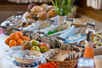 Das Fr&uuml;hst&uuml;cksbuffet im Gasthof-Metzgerei St&ouml;berl zeigt frisches Obst, Brot, Marmeladen und andere Auswahlm&ouml;glichkeiten auf einem gedeckten Tisch in einem gem&uuml;tlichen Raum.
