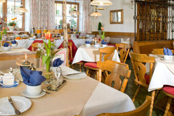 Gem&uuml;tlicher Restaurantbereich im Gasthof-Metzgerei St&ouml;berl mit gedeckten Tischen, Blumenarrangements und rustikaler Holzbestuhlung.