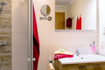 Sauberes Badezimmer mit Dusche, Handt&uuml;chern und Spiegel im Gasthof-Metzgerei St&ouml;berl f&uuml;r Komfort und Hygiene.