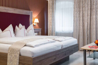 Hell eingerichtetes Doppelzimmer mit stilvollen wei&szlig;en Betttextilien und Vorh&auml;ngen im Gasthof-Metzgerei St&ouml;berl bietet Komfort und Gem&uuml;tlichkeit.