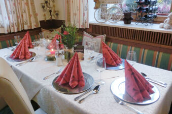 Tisch im Gasthof-Metzgerei St&ouml;berl mit festlich gedeckten Pl&auml;tzen, roten Servietten und dekorativen Elementen im Fensterbereich.