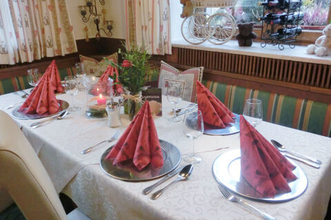 Tisch im Gasthof-Metzgerei St&ouml;berl mit festlich gedeckten Pl&auml;tzen, roten Servietten und dekorativen Elementen im Fensterbereich.