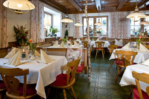 Gasthof-Metzgerei St&ouml;berl zeigt ein rustikales Restaurant mit wei&szlig;en Tischdecken, Holzm&ouml;beln und dekorativen Blumen auf den Tischen.