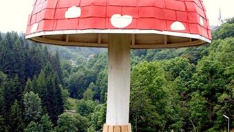 A large red and white spotted mushroom sculpture stands outdoors surrounded by trees at Hotel Post Nordhalben