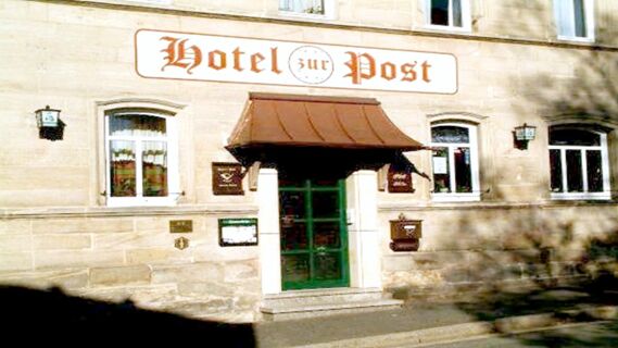 Front entrance of Hotel Post Nordhalben with a green door, brown canopy, and stone facade with windows and signage