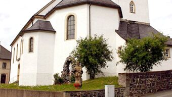 White historic building with small arched windows and greenery in front near a stone wall at Hotel Post Nordhalben