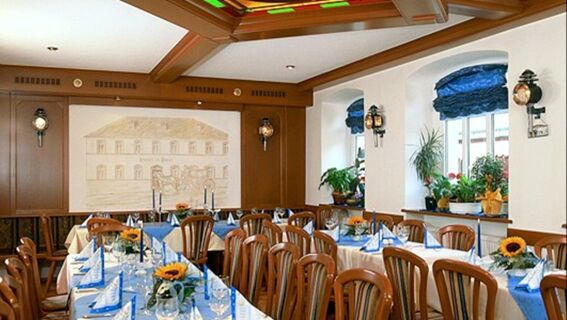 Dining room at Hotel Post Nordhalben with wooden chairs, tables set with blue napkins, candles, and sunflower centerpieces