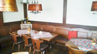 Gem&uuml;tlicher Aufenthaltsraum mit Holzm&ouml;beln und bunten Tischdecken im Gasthof Waldbrunner Hof, ideal zum Verweilen und Entspannen.