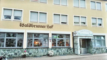 Fassade des Gasthofs Waldbrunner Hof mit mehreren Fenstern und einem Eingang unter einem Schild mit Hotel- und Restaurantnamen.