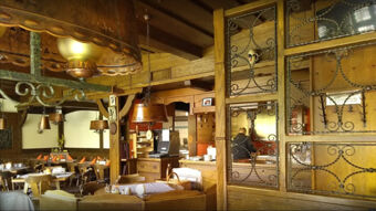 Gem&uuml;tlicher Gastraum im Gasthof Waldbrunner Hof mit dunklem Holzdekor, Tischen und klassischen Lampen f&uuml;r ein traditionelles Ambiente.
