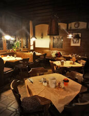 Rustikal eingerichtetes Restaurant mit Holztischen und St&uuml;hlen sowie warmem Licht im Gasthof Waldbrunner Hof, gem&uuml;tliche Atmosph&auml;re.