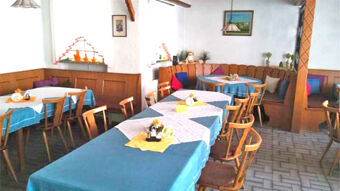 Gem&uuml;tlicher Gastraum mit blauen Tischdecken, Holzm&ouml;beln und dekorativen Details im Gasthof Waldbrunner Hof f&uuml;r entspannte Mahlzeiten.