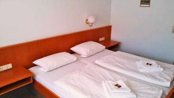 Ein einfach eingerichtetes Doppelzimmer mit zwei Betten und wei&szlig;en Bettwaren im Gasthof Waldbrunner Hof, ideal zum entspannten &Uuml;bernachten.