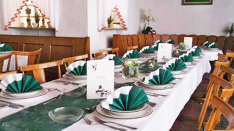 Festlich gedeckter Esstisch mit gr&uuml;nen und wei&szlig;en Servietten im Gasthof Waldbrunner Hof, ideal f&uuml;r Gruppenessen oder Feiern.