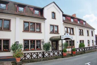 White two-story building with a red-tiled roof and windows with flowerpots at Posthotel Johannesberg entrance