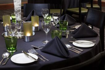 Table set with black napkins, green glasses, and candles at Holiday Inn London-Regent's Park dining area