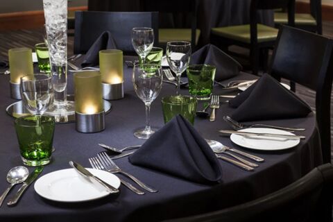 Table set with black napkins, green glasses, and candles at Holiday Inn London-Regent's Park dining area