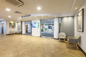 Entrance to The Academy conference room with glass doors and seating area inside Holiday Inn London-Regent's Park lobby