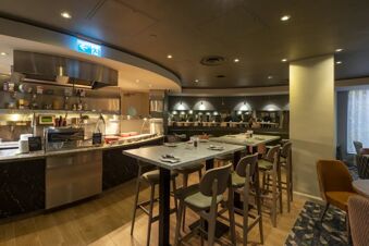 Dining area with high tables and chairs near a buffet counter in the Holiday Inn London-Regent's Park restaurant interior