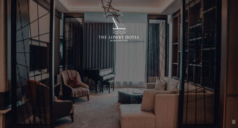 Living room with beige sofa, striped armchair, black grand piano, glass coffee table, and dark curtains at The Lowry Hotel Manchester