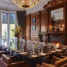 Elegant dining room at Hotel du Vin Glasgow with a large dark wood table set with glassware and floral centerpiece