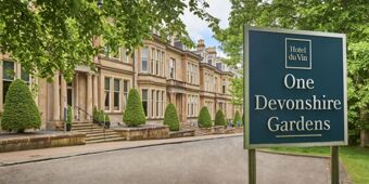 Sign for Hotel du Vin Glasgow at One Devonshire Gardens with beige stone building and neatly trimmed trees along the street