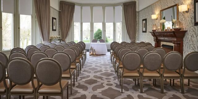 Rows of gray chairs facing a small white table near windows in a decorated room at Hotel du Vin Glasgow
