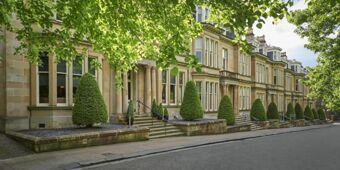 Elegant stone building with symmetrical windows, trimmed green bushes, and steps along a quiet street at Hotel du Vin Glasgow