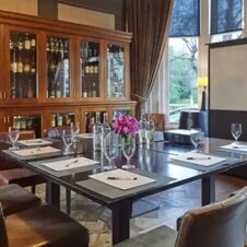 Conference room at Hotel du Vin Glasgow with a dark table set with glasses, notepads, pens, flowers, and bottles