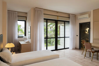 Twin beds with white linens next to a window and desk with lamp in a room at B&B Hotel Bari Rond&ograve;