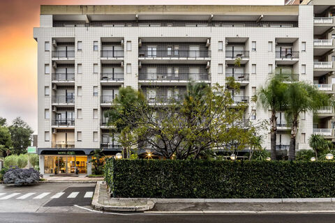 Multi-story building with balconies, palm trees, and greenery in front showing the entrance of B&B Hotel Bari Rond&ograve;
