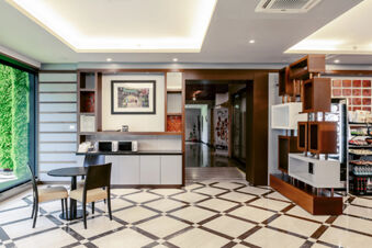 Open seating area with two black chairs and a table next to large window, microwave countertop and modern shelving at B&B Hotel Bari Rond&ograve;