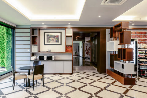 Open seating area with two black chairs and a table next to large window, microwave countertop and modern shelving at B&B Hotel Bari Rond&ograve;