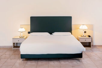 Double bed with black headboard, white bedding, two pillows, and bedside tables with lamps in B&B Hotel Bari Rond&ograve;