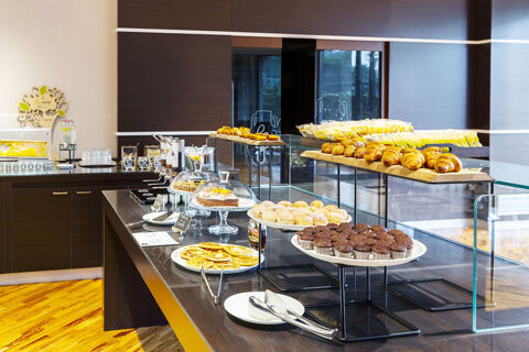 Breakfast buffet at B&B Hotel Bari Rond&ograve; with muffins, croissants, pastries, pancakes, and beverages on a dark wooden counter