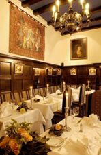 Dining area with white tablecloths, candles, floral arrangements, dark wood paneling, and tapestries at Burghotel Auf Sch&ouml;nburg
