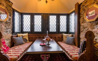 Cozy dining nook with patterned cushions and wooden benches in a room with leaded glass windows at Burghotel Auf Sch&ouml;nburg