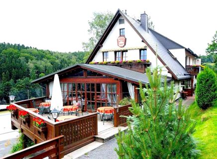 Gasthof u. Pension Waldeck с открытой площадкой и террасой в идиллическом лесном и горном пейзаже, деревенской архитектурой и столами с красными скатертями.
