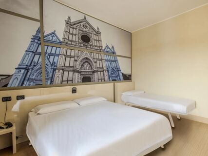 Room with a large double bed and a single bed, beige walls, wooden floor, and a large framed wall art at B&B Hotel Firenze Novoli