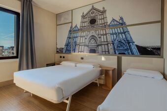 Two beds with white linens and wooden side tables under a large wall mural of a church at B&B Hotel Firenze Novoli
