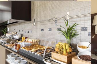 Breakfast buffet with pastries, fruits, cereals, juices, and labeled food items at B&B Hotel Arezzo dining area