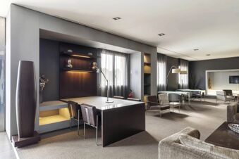 Open seating area with tables, chairs, floor lamps, and large windows with sheer curtains at B&B Hotel Arezzo