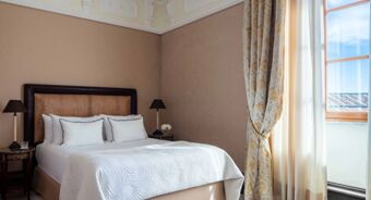 Bedroom with a neatly made bed, two bedside tables with lamps, patterned curtains, and a window at Anantara Palazzo Naiadi Rome Hotel Anantara Palazz