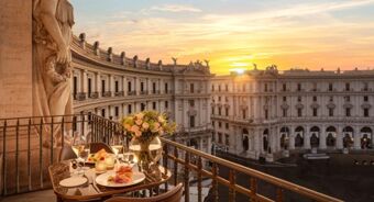 Balcony dining setup with flowers and food overlooking historic curved building at sunset at Anantara Palazzo Naiadi Rome Anantara Palazz