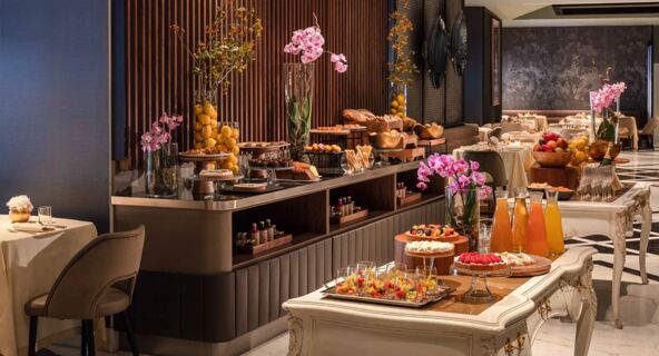 Buffet setup with pastries, fruit, juices, and floral decorations in a dining room at Anantara Palazzo Naiadi Rome Anantara Palazz