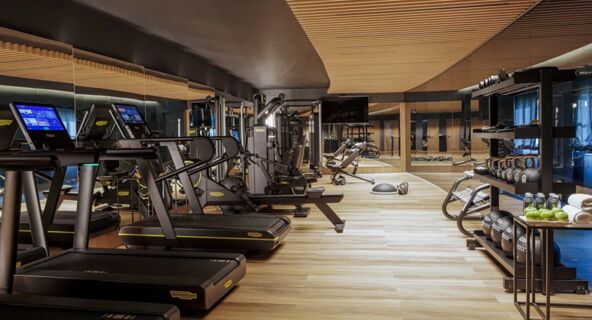Modern gym with treadmills, exercise machines, weights, kettlebells, benches, and wood ceiling at Anantara Palazzo Naiadi Rome Anantara Palazz